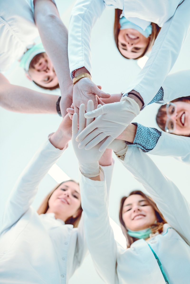 Ein Bild von 5 Personen die Ihre Hände in der Mitte übereinanderlegen